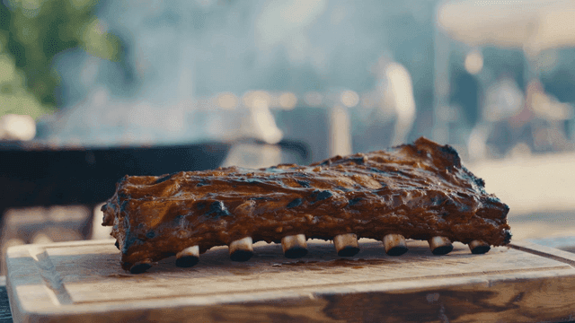 Grilled pork ribs cooked outdoors on wooden cutting board