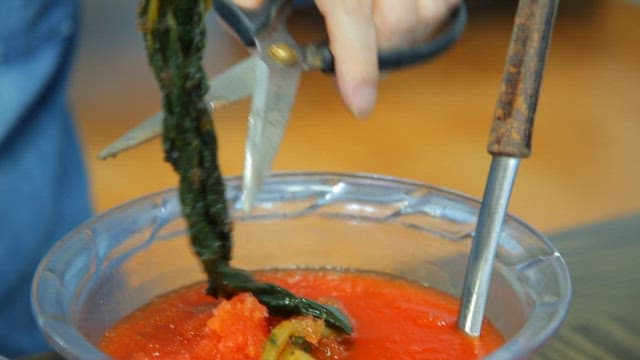 Adding yeolmu kimchi to cold noodles in a bowl