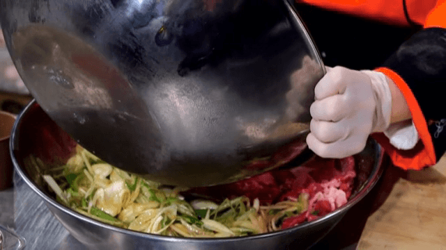 큰 그릇에 소고기와 채소를 섞는 장면