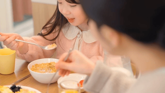 Child enjoying breakfast with family