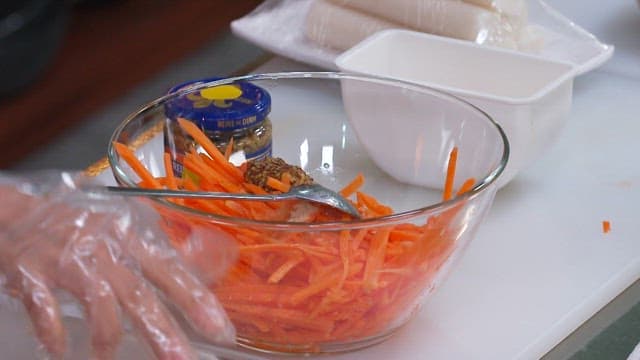 Seasoning Shredded Carrots in a Glass Bowl