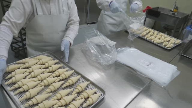 Placing croissant dough on a baking tray in an industrial kitchen