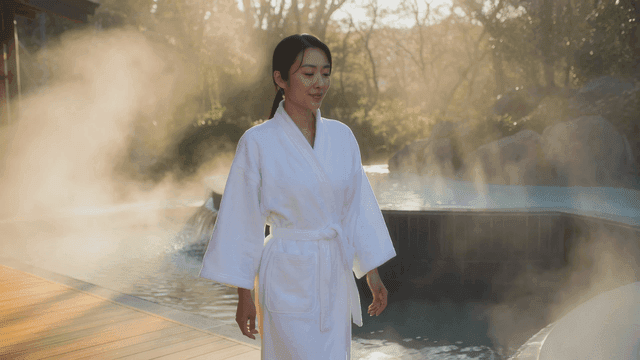 Woman wearing robe next to steaming hot spring
