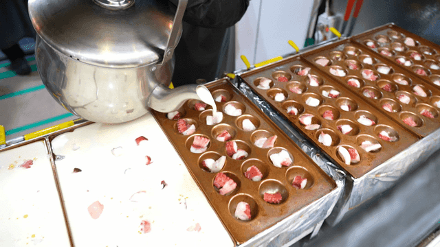 Takoyaki batter poured from kettle into mold