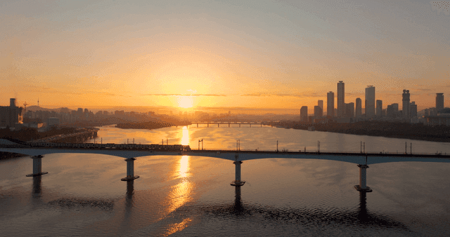 일몰 강 위의 다리를 건너는 기차