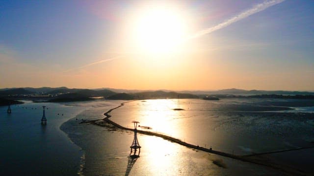 Scenic sunset over a calm sea with cable car towers