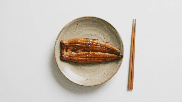 Grilled eel with soy sauce seasoning on ceramic plate with chopsticks
