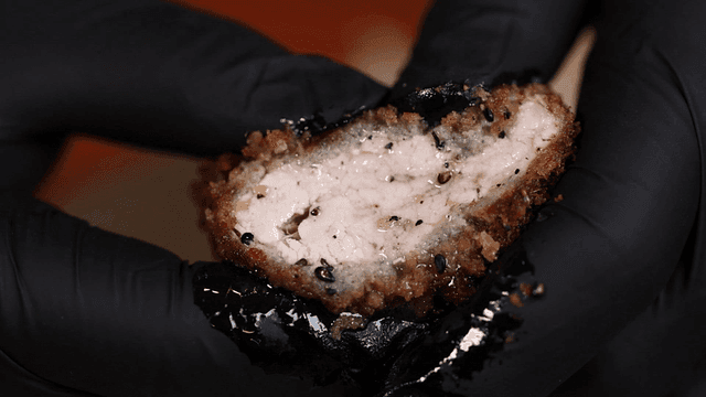 Juicy pork cutlet held in gloved hand