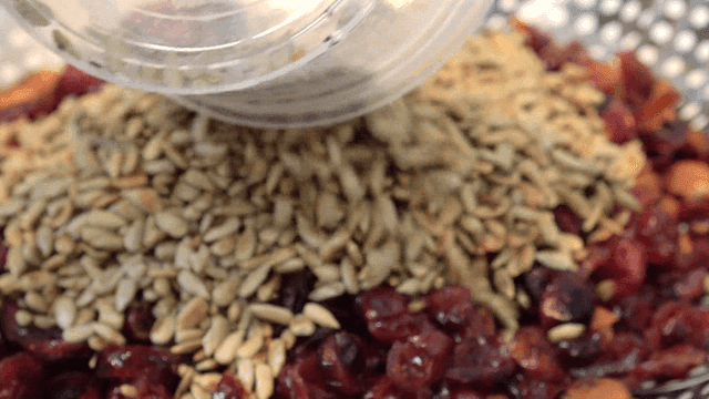 Roasted sunflower seeds poured onto almonds and cranberries