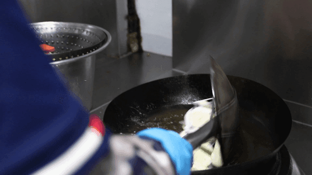 Sliced eggplants being deep-fried in oil