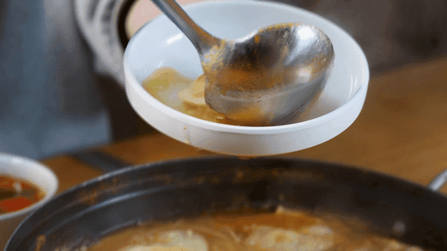 Person who serves dumpling hot pot onto plate to eat