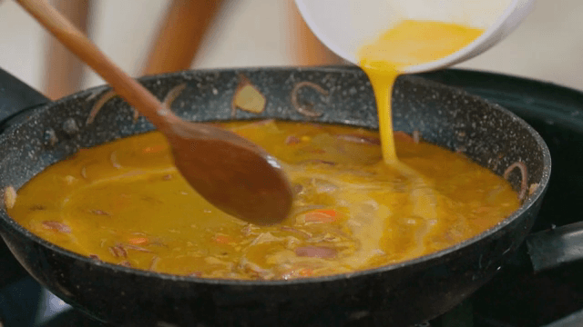 Pouring egg mixture into a frying pan
