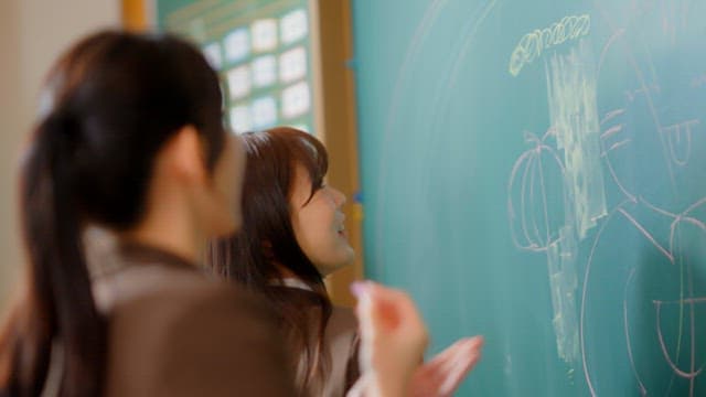 Students scribbling on a classroom blackboard