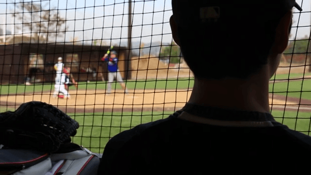 Baseball player watching a game from the dugout