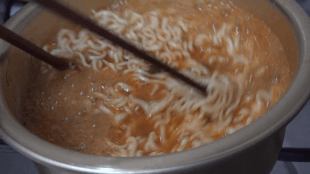 Ramen boiling in a pot with chopsticks