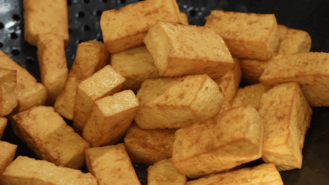 Golden fried tofu pieces in a strainer