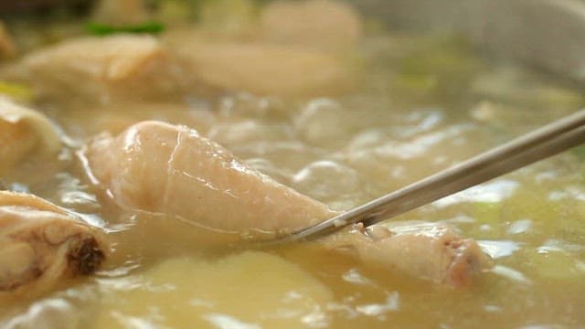 닭고기 한 조각을 젓가락으로 집어올리는 장면