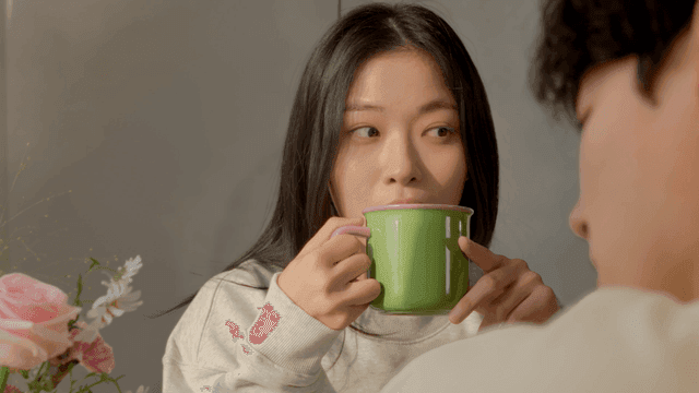 Woman enjoying warm drink in cozy home with couple