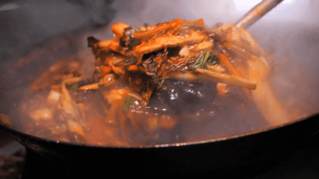 Ladleful of steaming Sundubu Jjamppong from wok