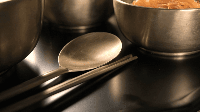 Metal bowls, spoons, and chopsticks on table