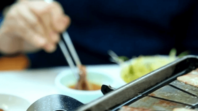 삼겹살을 참기름장에 찍는 모습