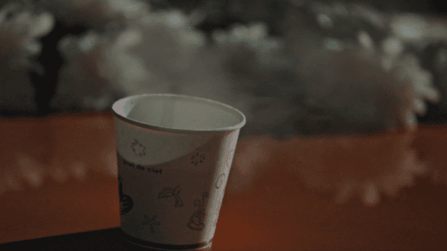 Steaming coffee paper cup on a table