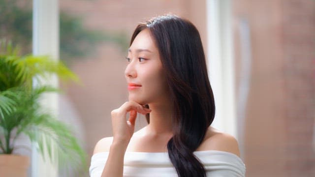 창문으로 햇빛이 들어오는 방에서 활짝 미소짓는 여성의 얼굴