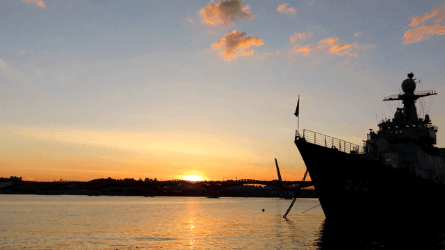 Boat by bridge at sunset.