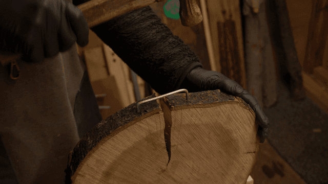 통나무 판에 고정 와이어를 망치로 박는 공예가