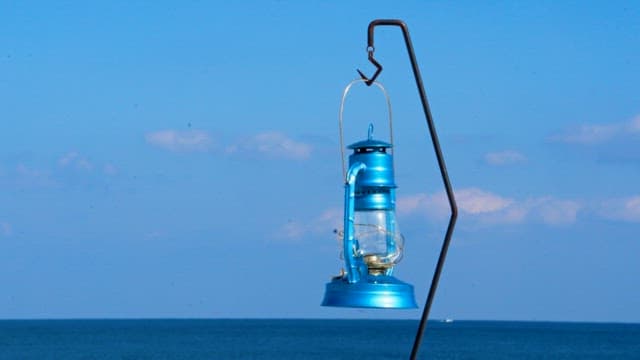 Blue camping lantern hanging by the seaside on a clear day