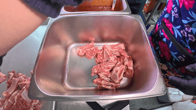 Person placing raw meat on metal tray