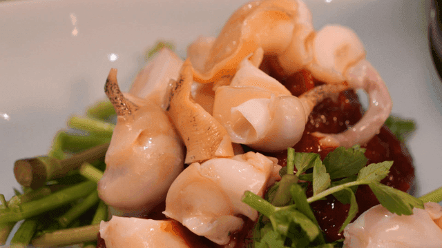 Whelk on top of fresh vegetables and sauce