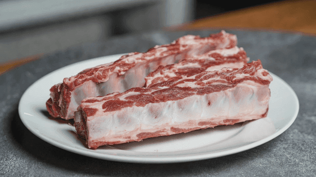 Raw beef ribs on a white plate