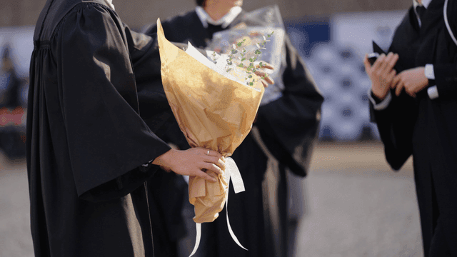 Graduates holding bouquets of flowers