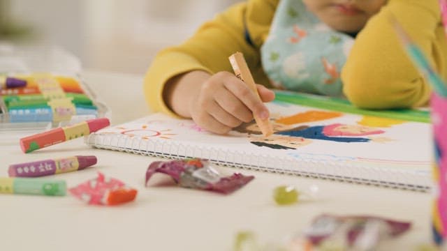 Child focused on drawing with crayons