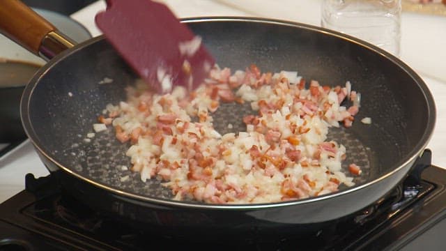 Stir-frying minced onions and bacon in a frying pan