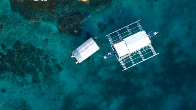 Bangka floating on the clear blue sea near the coastal cliffs