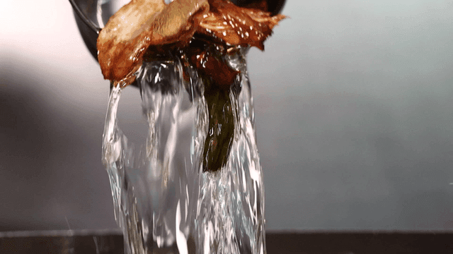Oil from frying green onions and onions pouring out of ladle