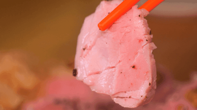 Pink piece of sous vide sirloin picked up with chopsticks