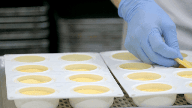 Baker placing cookies into mold with gloved hands