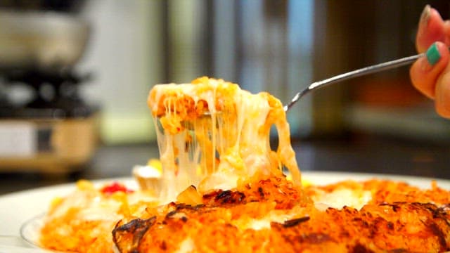 Spoonful of cheese-covered kimchi fried rice on a plate