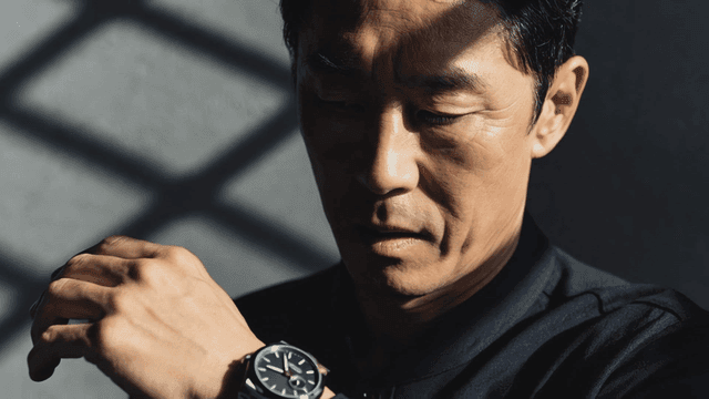 어두운 곳에서 손목시계로 시간을 확인하는 중년 남자