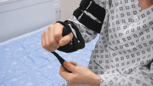 Patient adjusting arm brace in hospital
