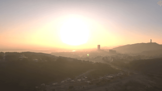 멀리 언덕이 보이는 고요한 바다의 일출