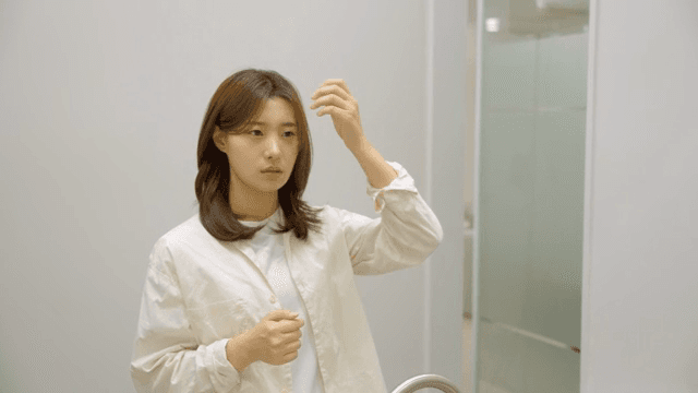 Woman adjusting her hair in front of a mirror