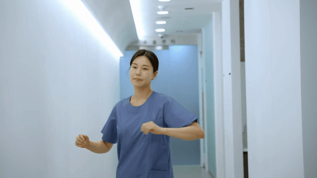 스트레칭을 하며 병원 복도를 걸어가는 간호사