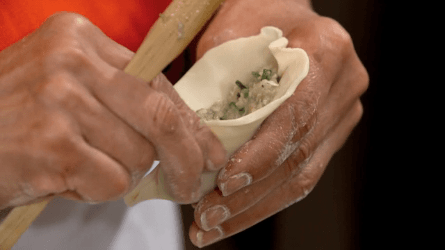 Hands making dumplings with filling