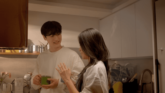 부엌에서 따뜻한 음료 들고 대화하는 커플