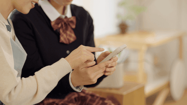 Two friends using a smartphone indoors