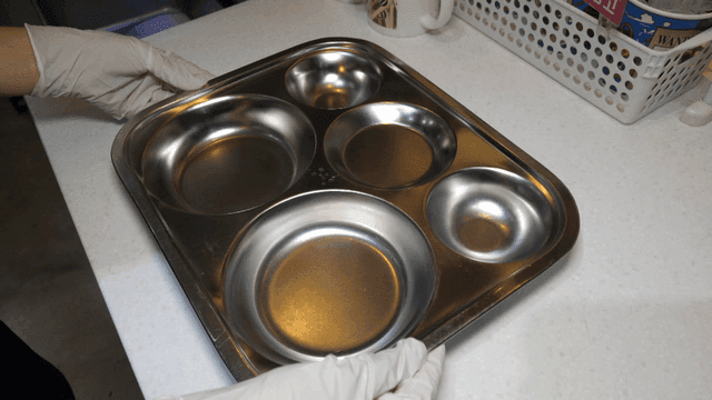 테이블에 금속 트레이를 놓는 사람